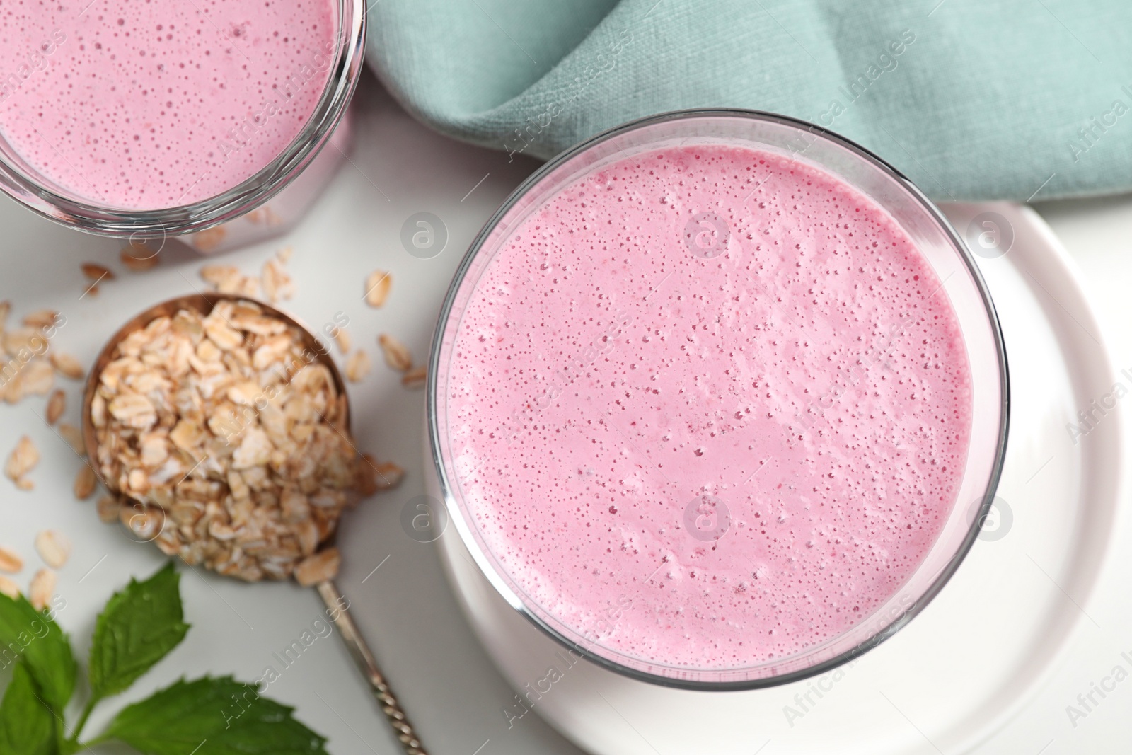 Photo of Glasses of blackberry smoothie and oatmeal on white table, flat lay