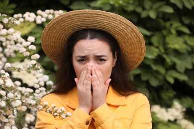 Woman suffering from seasonal pollen allergy near blossoming tree on spring day