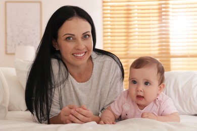Photo of Happy woman with her little baby on bed at home