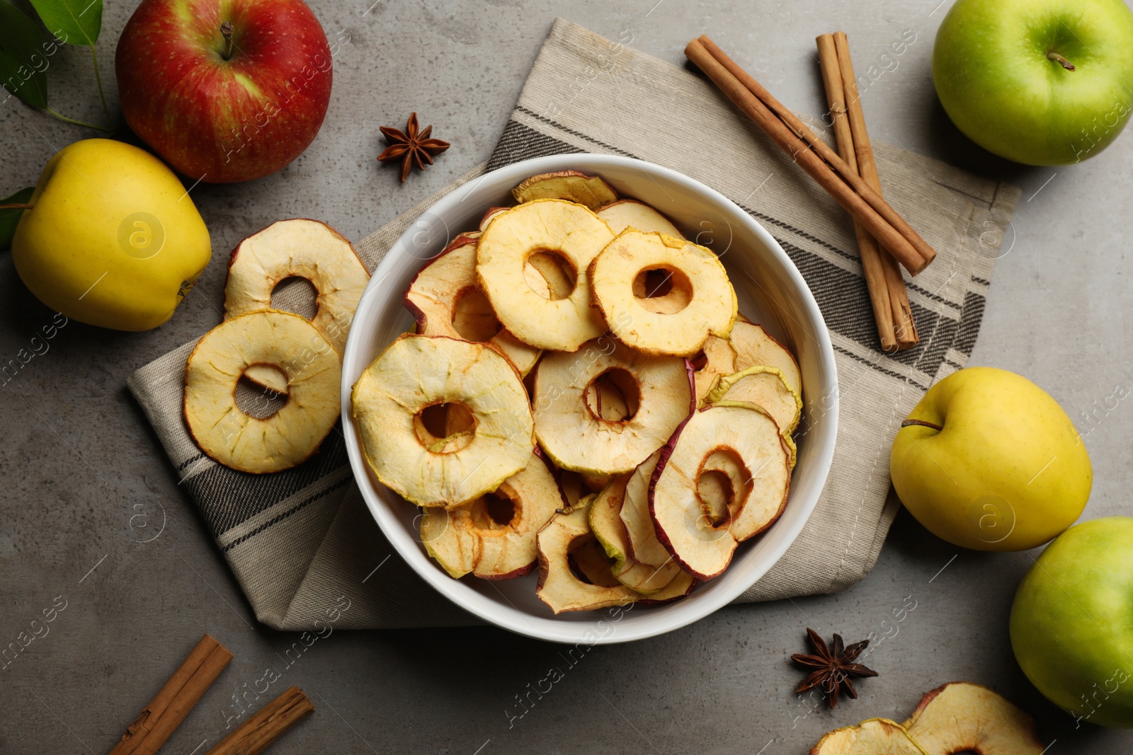 Photo of Delicious apple chips, fresh fruits, anise and cinnamon on grey table, flat lay