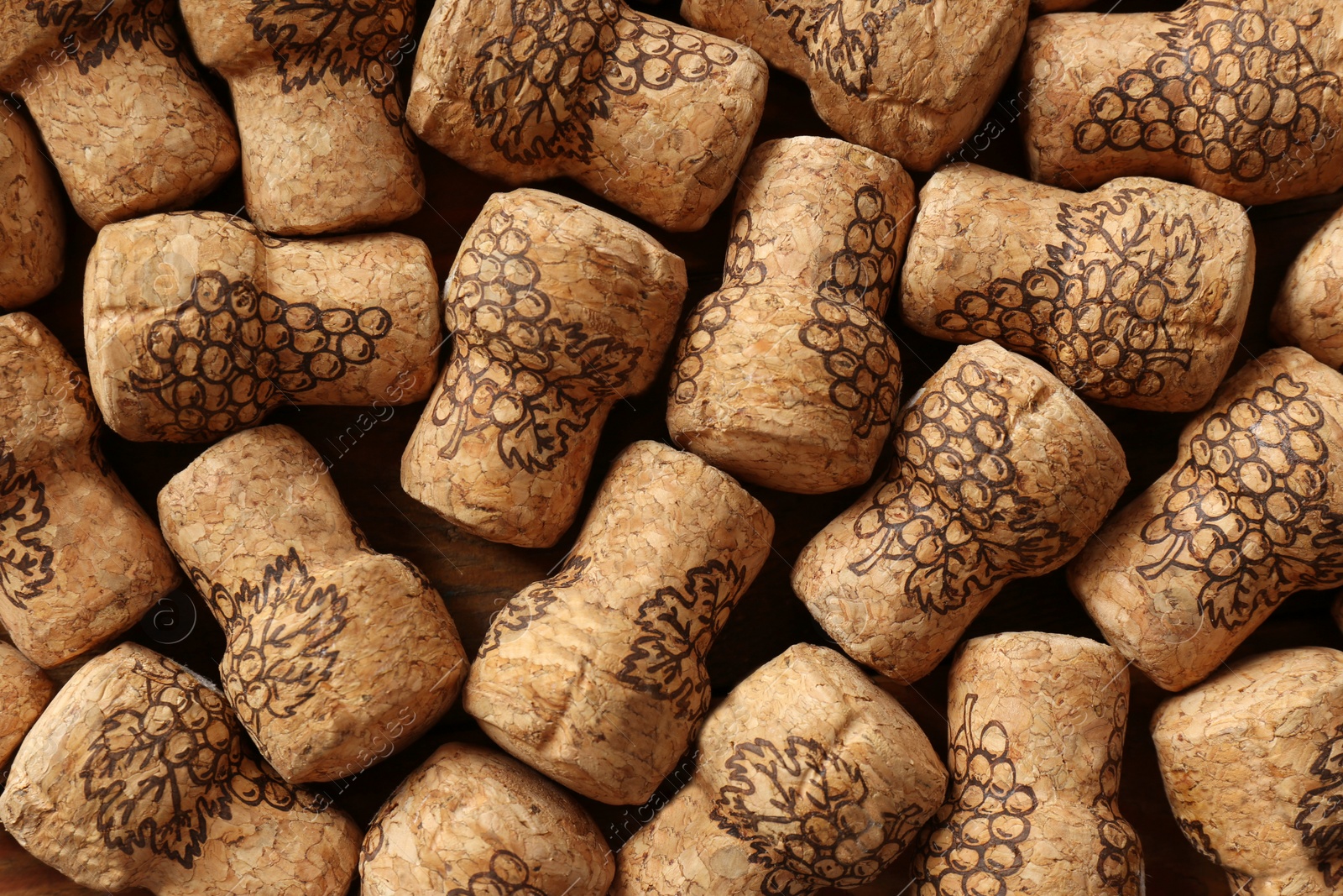 Photo of Many corks of wine bottles with grape images as background, top view