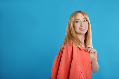 Photo of Beautiful young woman with blonde hair on blue background. Space for text