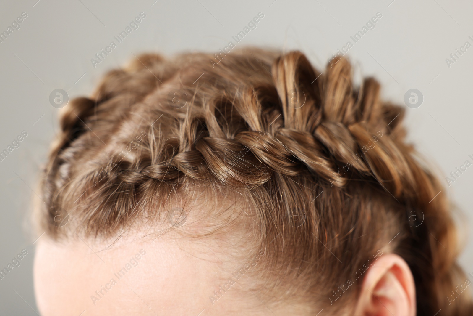 Photo of Woman with braided hair on grey background, closeup