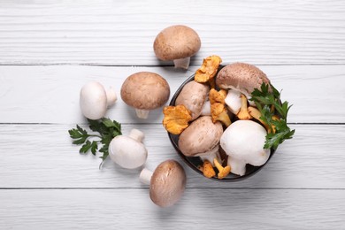 Photo of Bowl with different mushrooms and parsley on white wooden table, flat lay