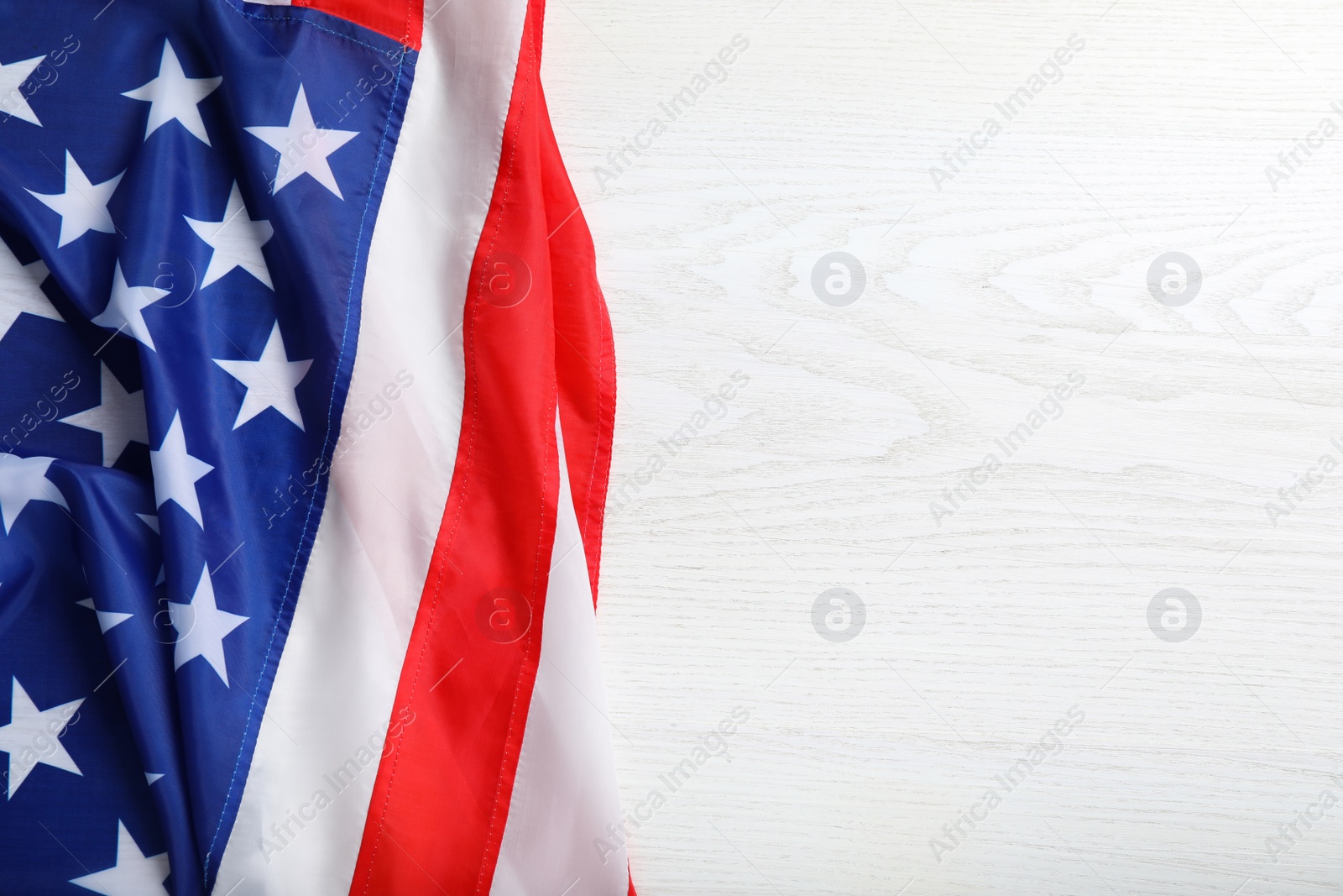 Photo of American flag on white wooden table, top view. Space for text