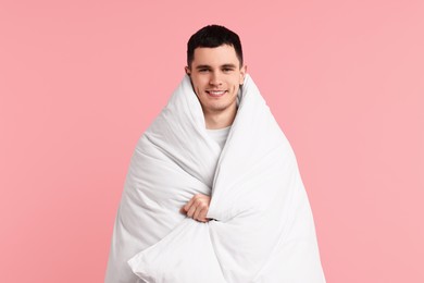 Happy man wrapped in blanket on pink background