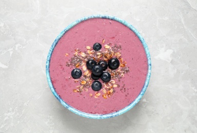 Photo of Delicious acai smoothie with granola and chia seeds in dessert bowl on grey table, top view