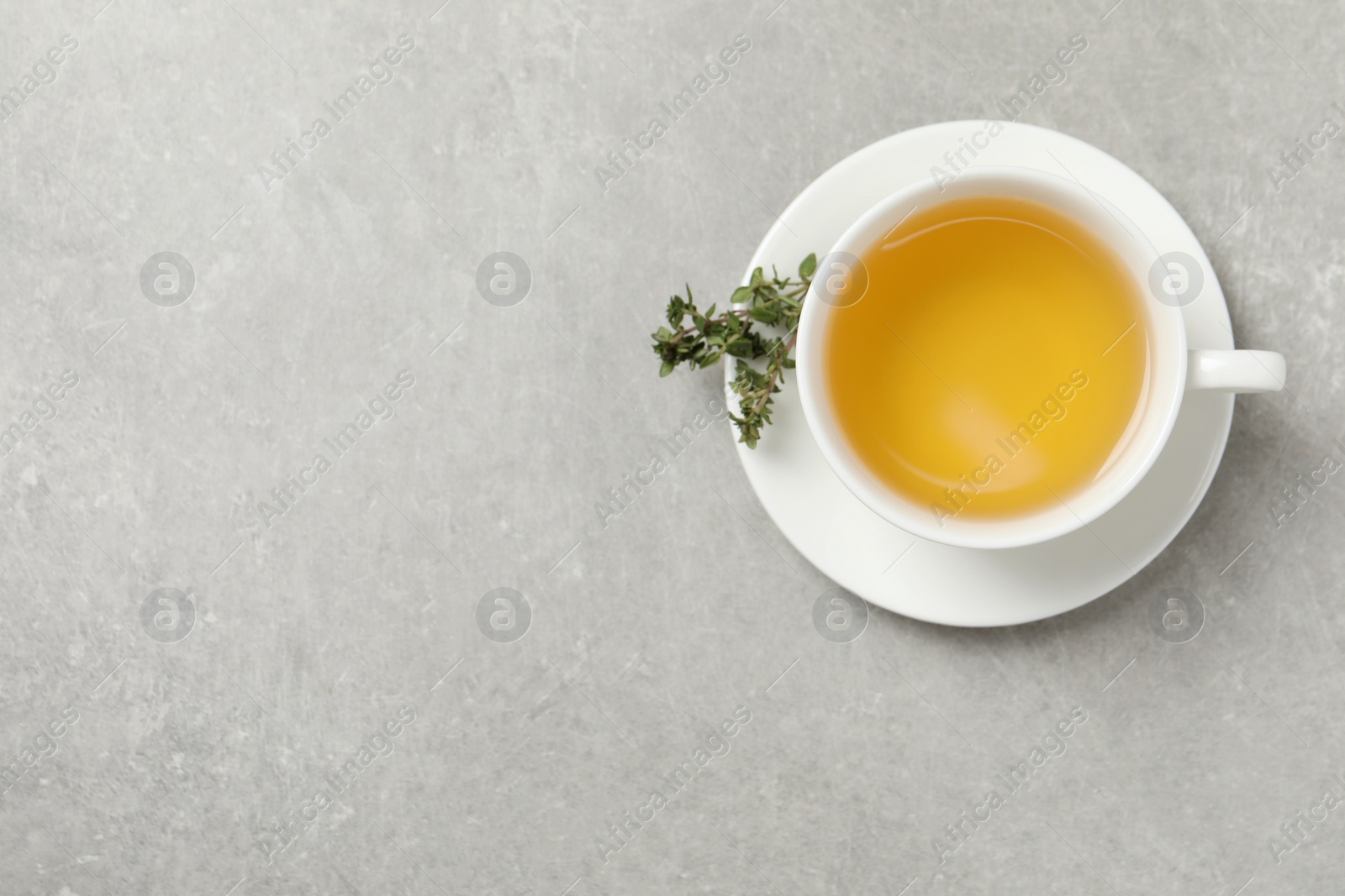 Photo of Aromatic herbal tea with thyme on light grey table, top view. Space for text
