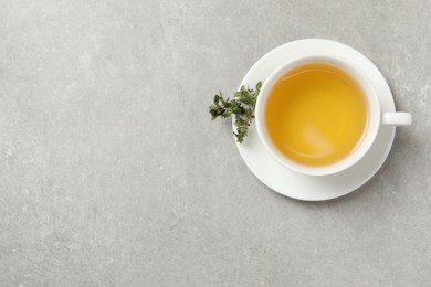 Aromatic herbal tea with thyme on light grey table, top view. Space for text