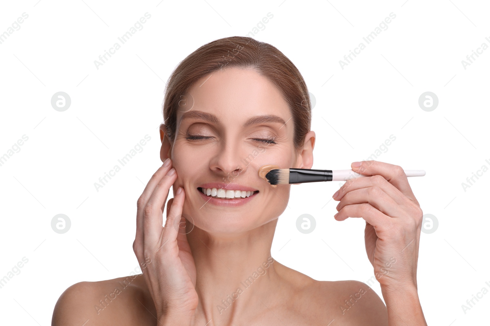 Photo of Woman applying foundation on face with brush against white background