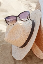 Photo of Hat with beautiful sunglasses on sandy beach