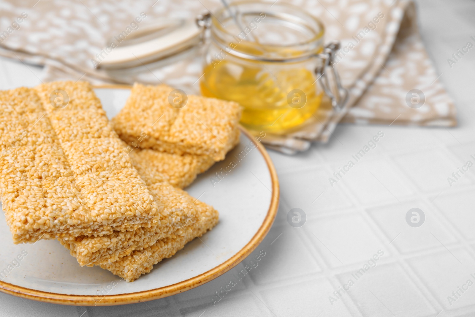 Photo of Plate with delicious sesame kozinaki bars on white table, closeup. Space for text