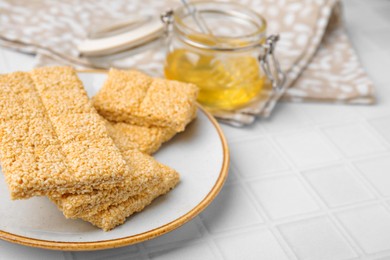 Photo of Plate with delicious sesame kozinaki bars on white table, closeup. Space for text