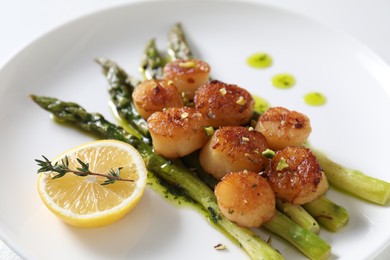 Delicious fried scallops with asparagus, lemon and thyme on white background, closeup