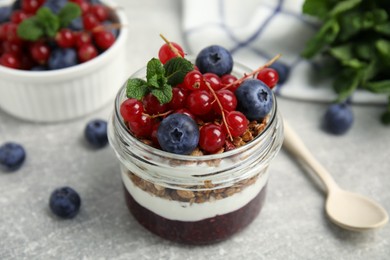 Photo of Delicious yogurt parfait with fresh berries and mint on light grey table, closeup
