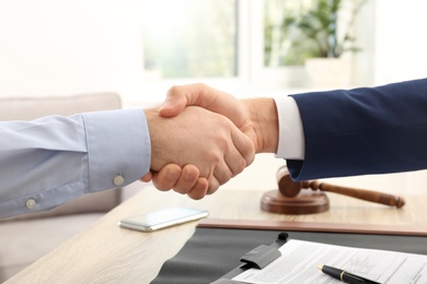 Photo of Lawyer handshaking with client over table in office, closeup