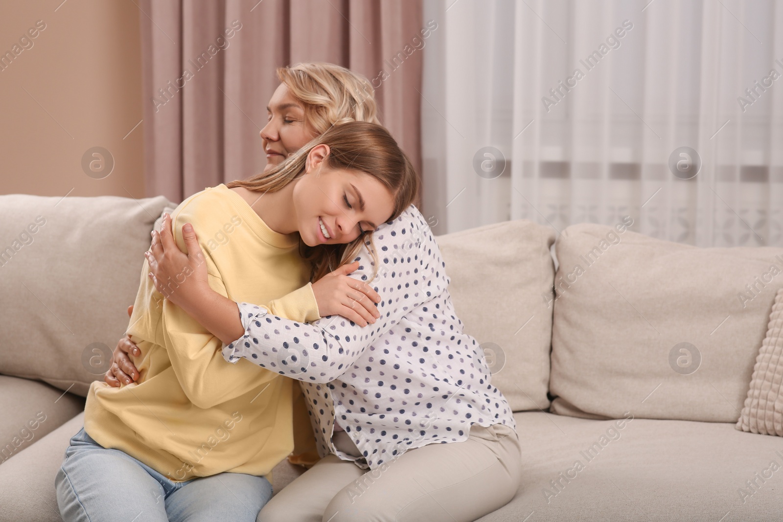 Photo of Young woman with her mom on sofa at home. Happy Mother's Day