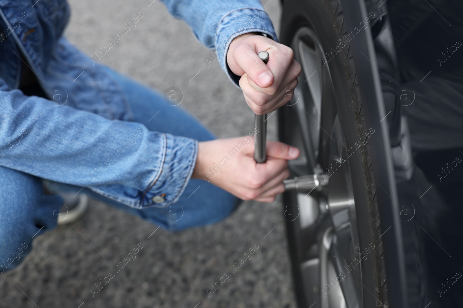 Photo of Young man changing tire of car on roadside, closeup