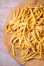 Photo of Board with homemade pasta on wooden table, top view