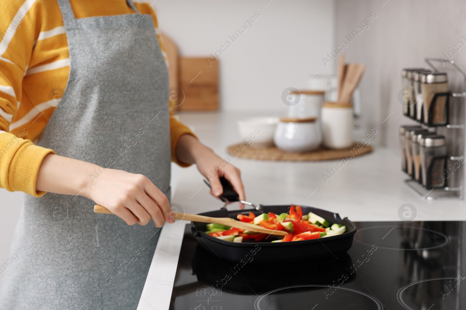Photo of Woman cooking vegetable dish on cooktop in kitchen, closeup