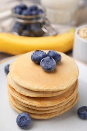 Photo of Tasty oatmeal pancakes with blueberries on plate, closeup