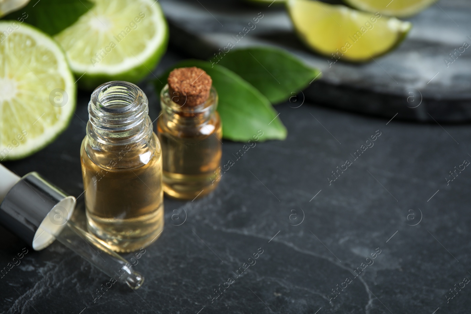 Photo of Bottles of citrus essential oil on black table. Space for text