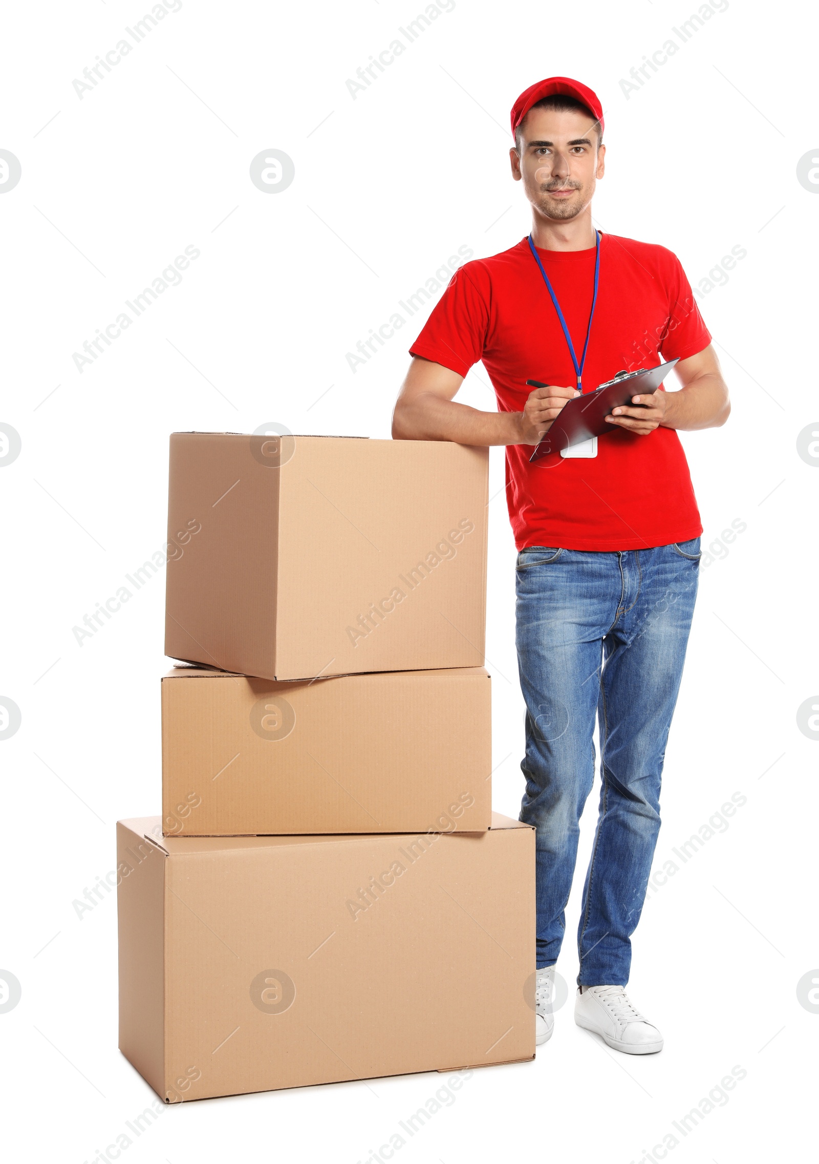 Photo of Young happy courier with clipboard near pile of cardboard boxes on white background