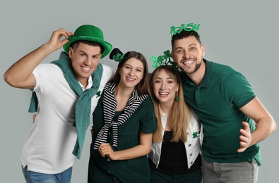 Photo of Happy people in St Patrick's Day outfits on light grey background