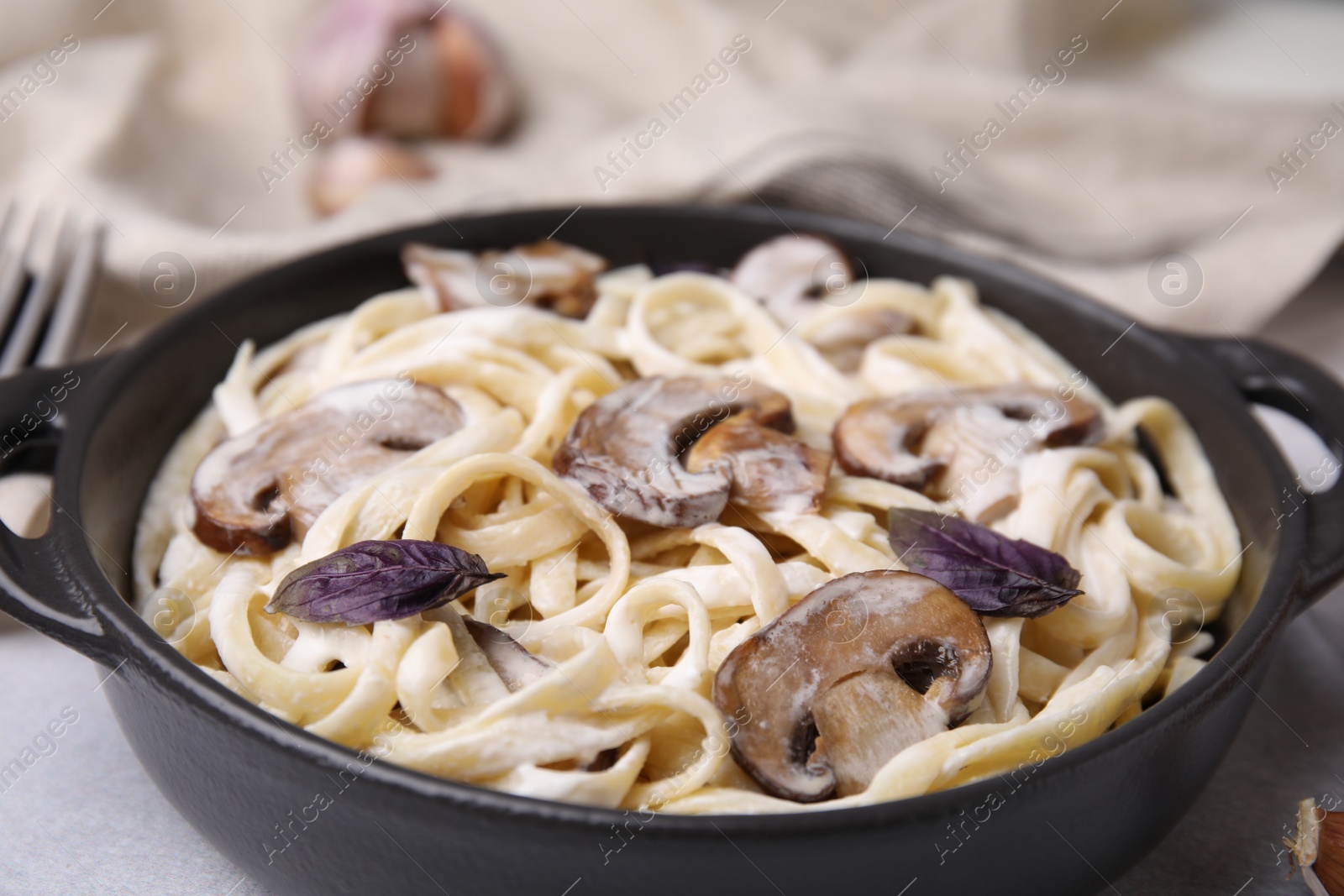 Photo of Delicious pasta with mushrooms on grey table, closeup