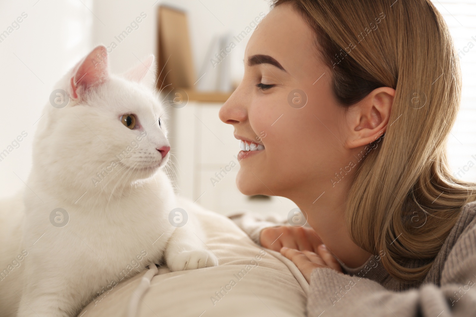 Photo of Young woman with her beautiful white cat at home. Fluffy pet