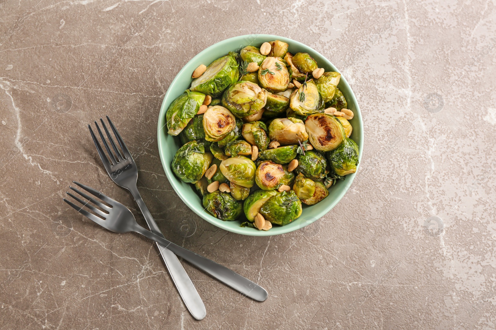 Photo of Delicious roasted brussels sprouts with peanuts on grey marble table, flat lay