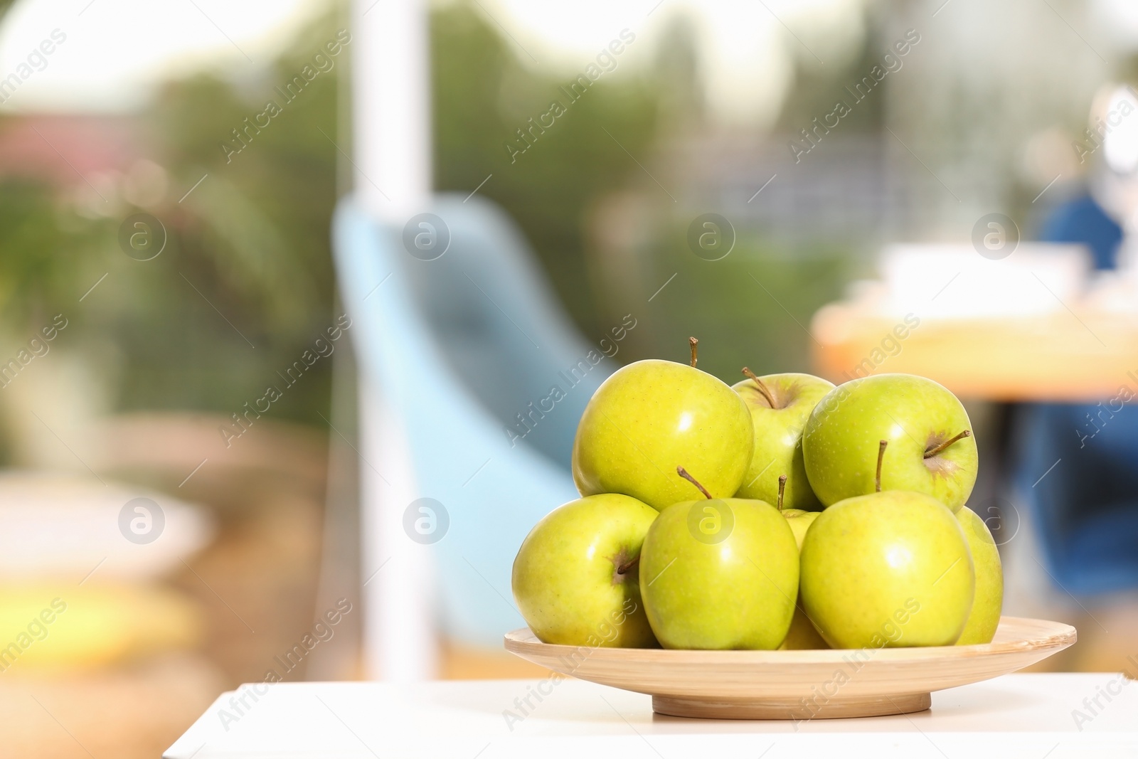 Photo of Plate with sweet green apples on table in room, space for text