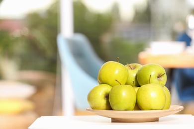 Photo of Plate with sweet green apples on table in room, space for text