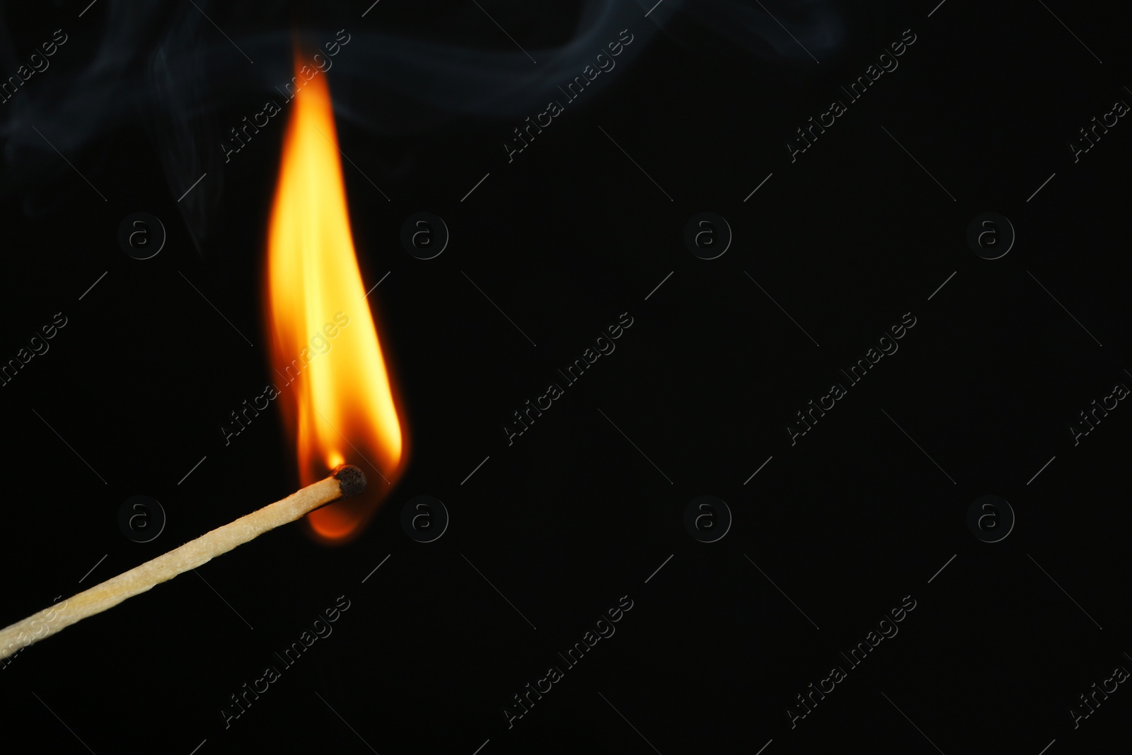 Photo of Burning matchstick on black background, closeup. Space for text