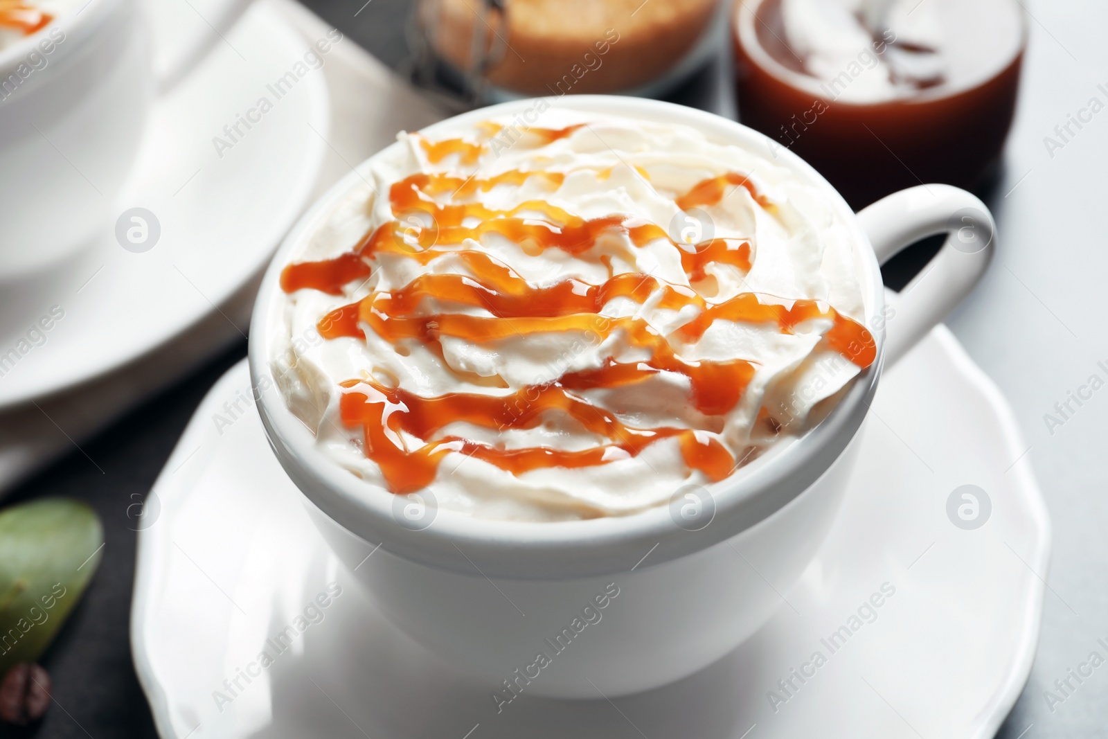 Photo of Cup of coffee with caramel topping on table, closeup