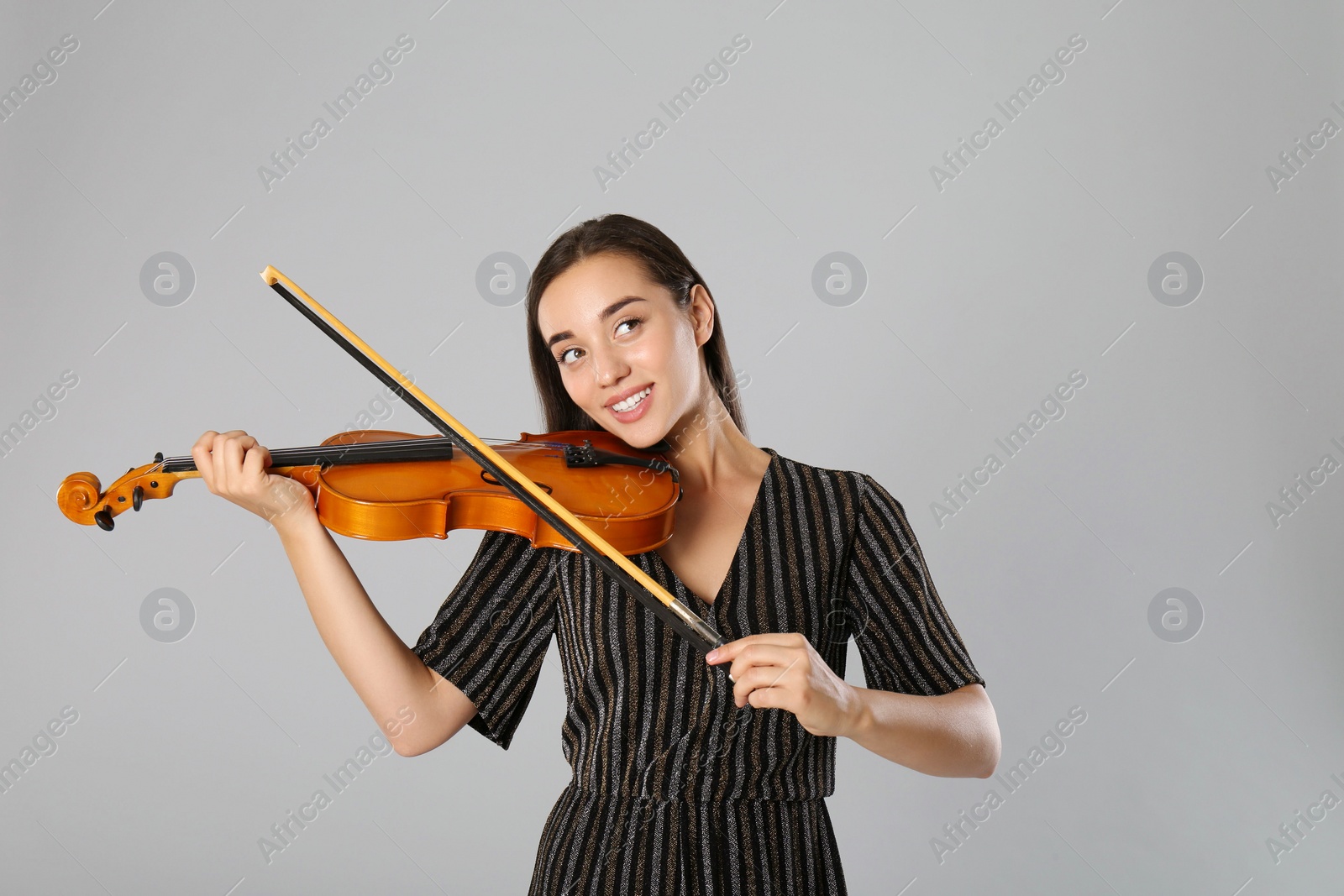 Photo of Beautiful woman playing violin on grey background