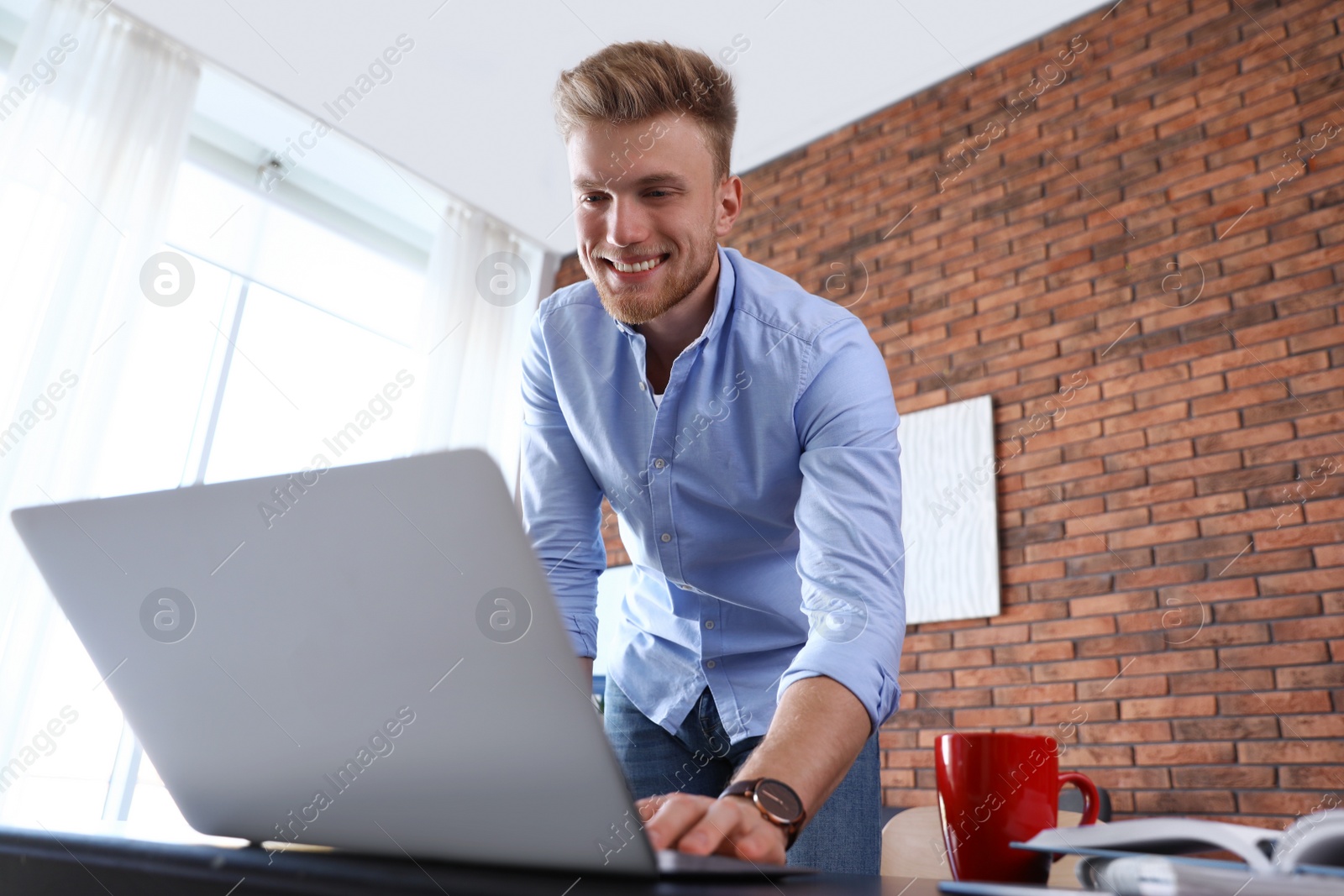 Photo of Young man using laptop at table indoors