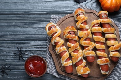 Photo of Cute sausage mummies served on wooden table, flat lay. Halloween party food