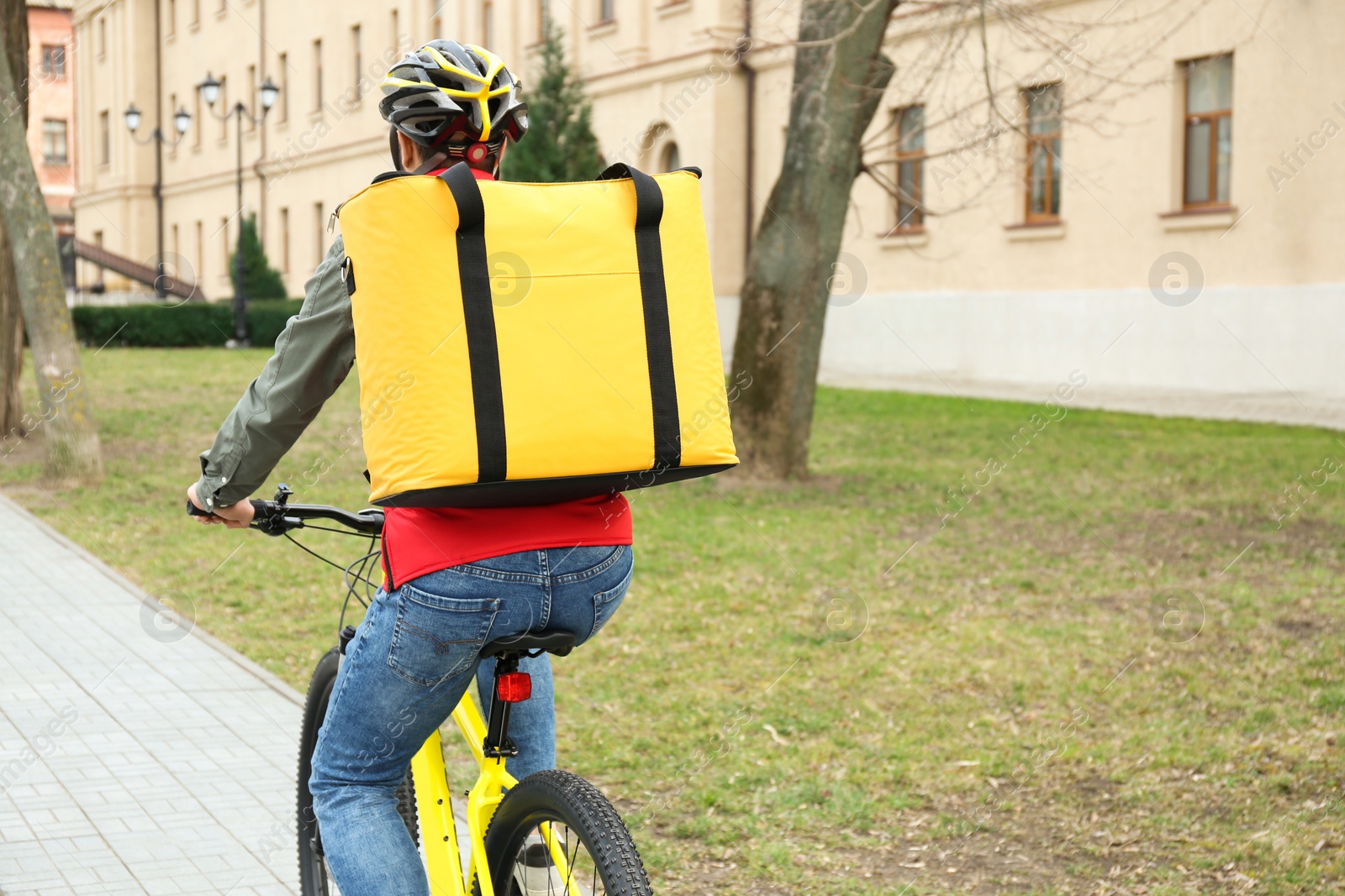 Photo of Courier with thermo bag riding bicycle outdoors. Food delivery service