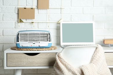 Photo of Modern air purifier near laptop on white wooden table in room