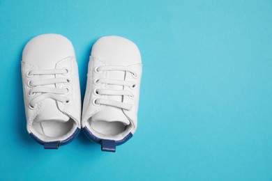 Photo of Cute baby shoes on light blue background, flat lay. Space for text