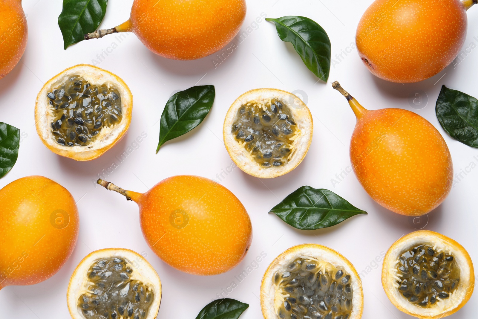 Photo of Delicious ripe granadillas and leaves on white background, flat lay