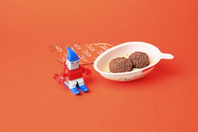 Photo of Slynchev Bryag, Bulgaria - May 25, 2023: Half of Kinder Joy Egg with sweet candies and toy on orange background