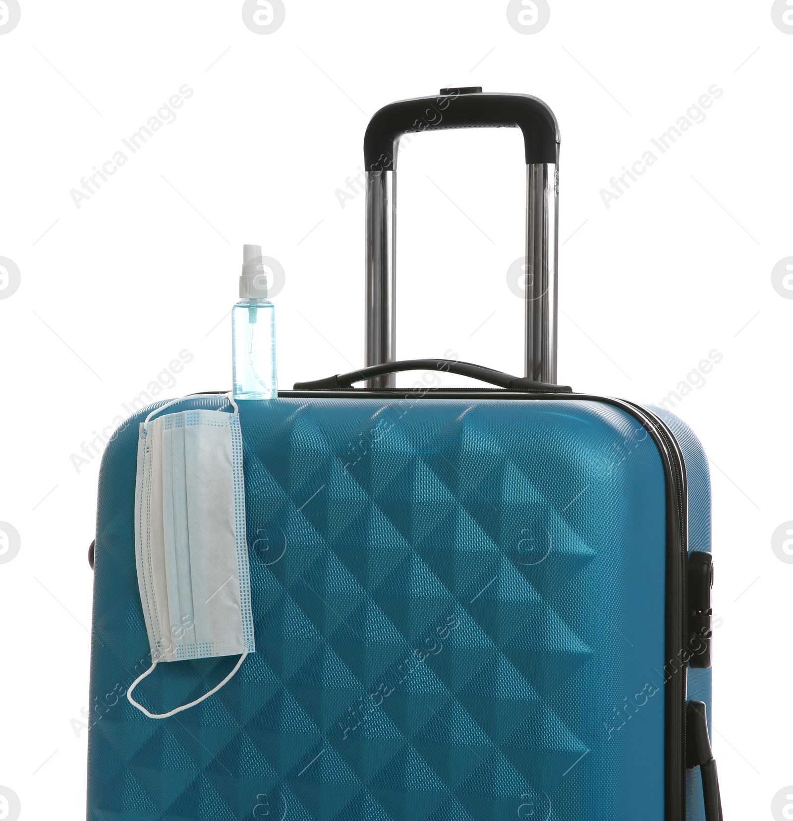 Photo of Stylish blue suitcase, antiseptic spray and protective mask on white background. Travelling during coronavirus pandemic