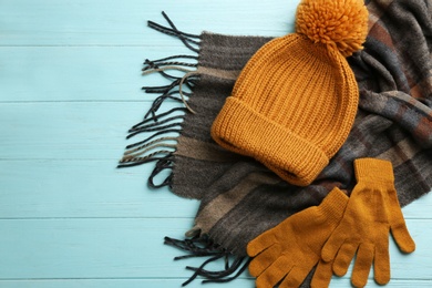 Photo of Stylish gloves, scarf and hat on light blue wooden background, flat lay. Space for text