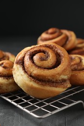 Photo of Tasty cinnamon rolls on black table, closeup. Space for text