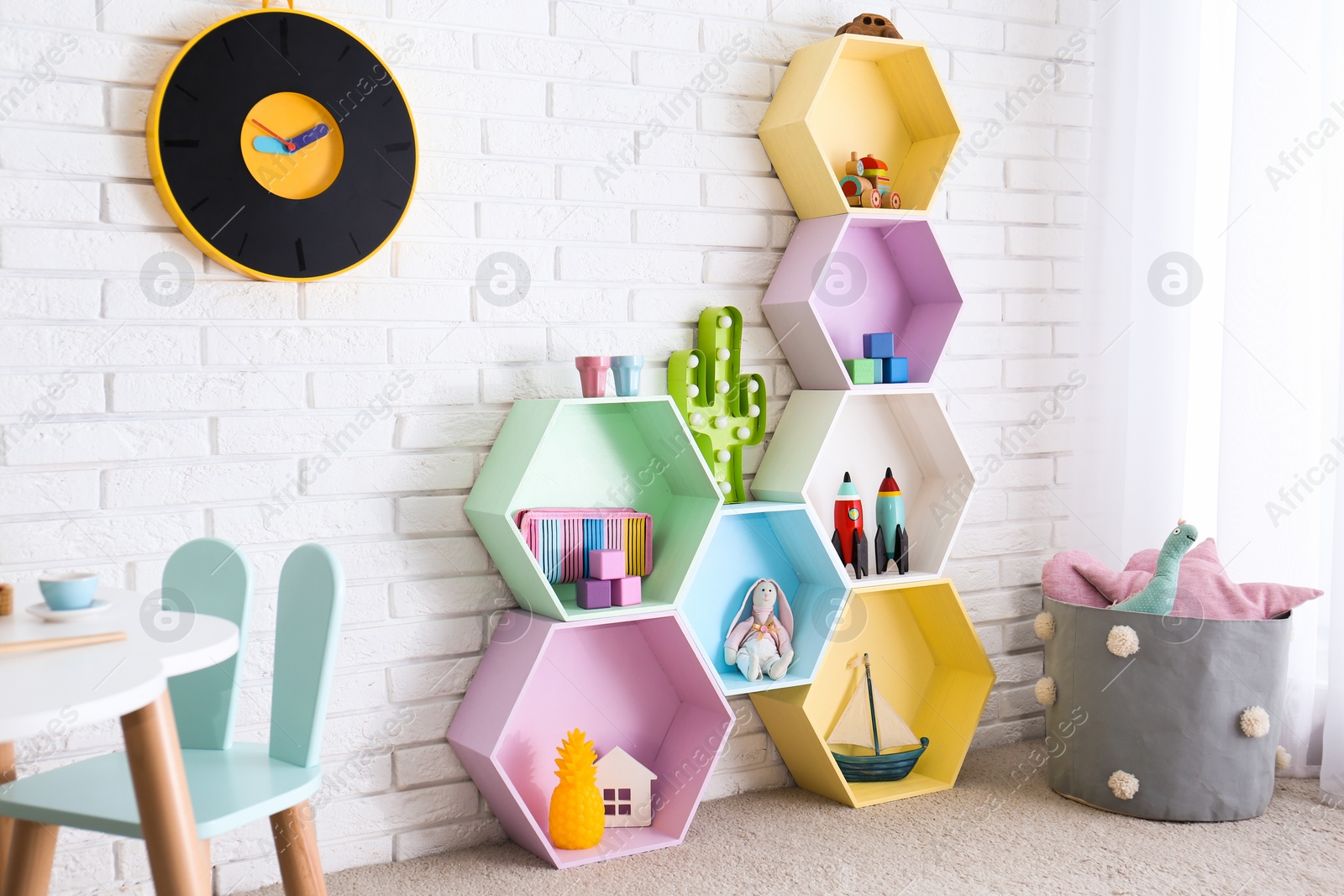 Photo of Child room interior with colorful shelves near brick wall