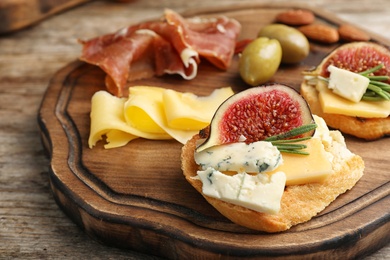 Photo of Sandwich with ripe figs and delicious products on wooden board, closeup