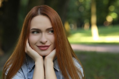 Photo of Portrait of beautiful young woman with red hair outdoors. Space for text. Attractive lady posing for camera
