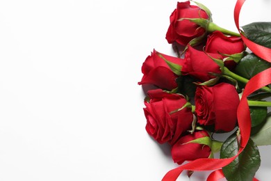 Photo of Beautiful red roses and ribbon on white background, top view. Space for text